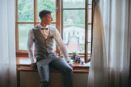 stylish groom in a bow tie posing in the hotelの写真素材