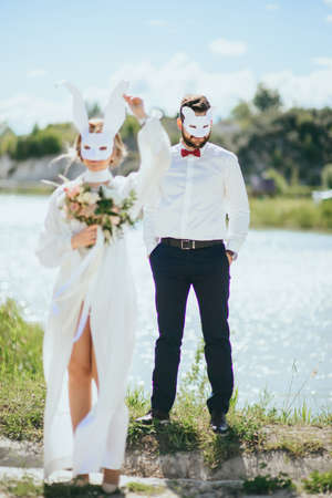 bearded groom and beautiful bride posing in rabbit masksの写真素材