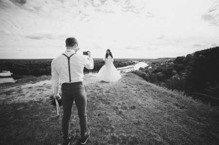 The bride is gathering in the morning. Stylish lush white wedding dress. Hotel room. Portrait of the bride. Veil.The bride is photographed on a mobile phone.の写真素材