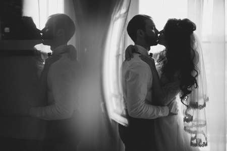 The groom and bride sitting against the background of a large window.の写真素材