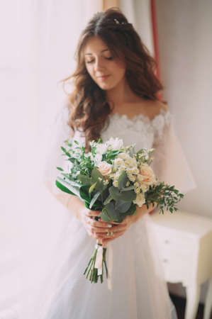 Very beautiful bride with her delicate bouquet posing near the castleの写真素材