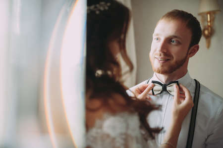 Attractive young bride adjusting the bow tie of her man.の写真素材
