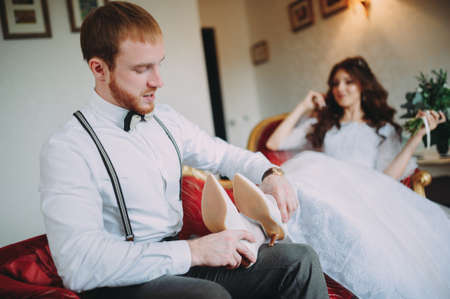 Bride and groom sitting at the bar on the couch. Cute married couple in cafe, groom kissing a bride. Pure tendernessの写真素材