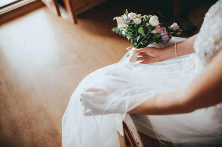 Fashion photo of a beautiful bride with flowers bouquet in her hands at the light room next to the doorsの写真素材