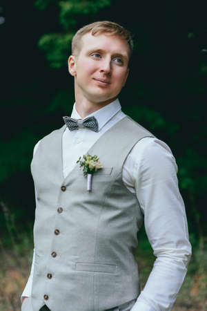 A handsome groom looks happy on his wedding day in grey and yellow.の写真素材