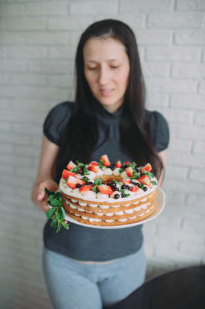 fruit cake with strawberries mint and blueberry in handsの写真素材