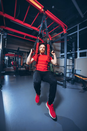 Strong woman using a resistance band in her exercise routine. Female athlete exercising with resistance band in studio.の写真素材