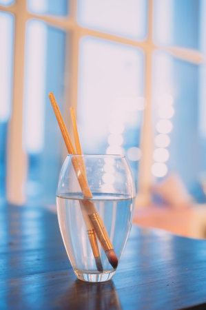 paint brushes in a glass of water. blue backgroundの写真素材