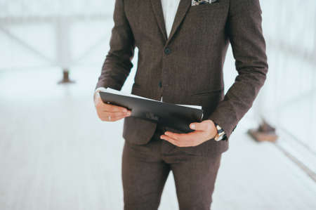 Confident businessman with US dollar bills in suit and hold tablet computer in the foreground front his team,Successful team leader and business owner leading informal in-house business meeting,の写真素材