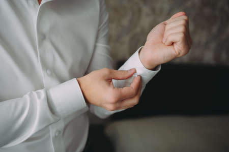 groom buttoning the shirt. wedding preparations. white shirtの写真素材