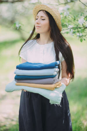 cropped image of smiling seamstress holding stack of colored fabricの写真素材