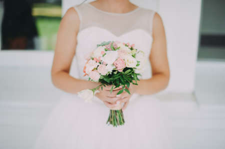 A beautiful bride is holding a wedding bouquetの写真素材