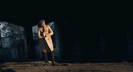 stylish guy in a coat and cap on a dark backgroundの写真素材