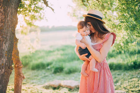 Beautiful mother in a pink sundress with a child 1-2 year old in nature Summer season. Motherhood. Family time.の写真素材