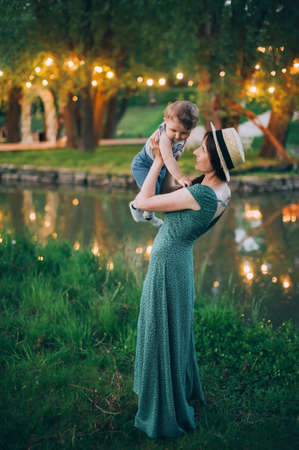 Happy mother with one year old baby on the background of lights. Lakeの写真素材