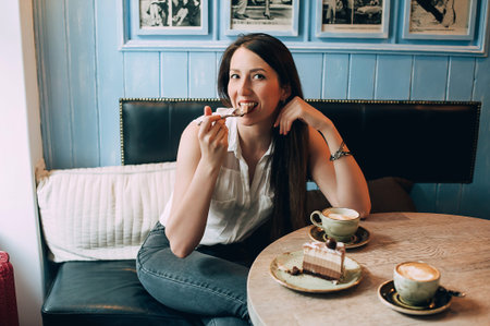 stylish girl drinks coffee and eats cake in a cafe