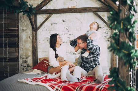 young family mom dad and year-old son on the bed. having fun. love. tendernessの写真素材