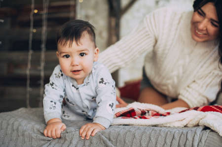 Portrait of young mother with her sweet newborn baby child in white wear having fun in the bedroom at morning, loving happy family concept. studio shot.の写真素材