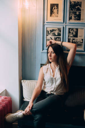 Young stylish girl posing in a cafe. dressed in stylish high waisted jeans. Fashionable European girl.の写真素材