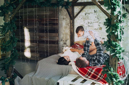 young family mom dad and year-old son on the bed. having fun. love. tendernessの写真素材