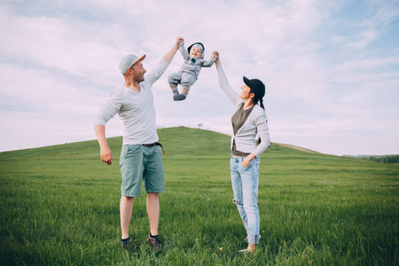 Happy parents throw up a child in nature on a green field. The concept of happiness, family Active...