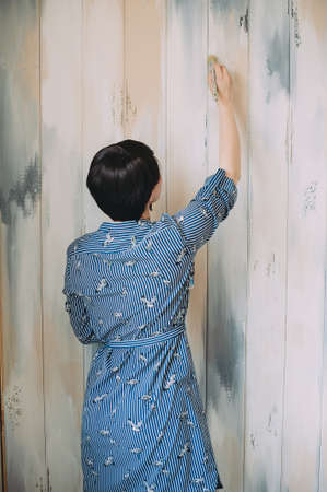 Young asian happy woman painting interior wall with paint roller in new houseの写真素材