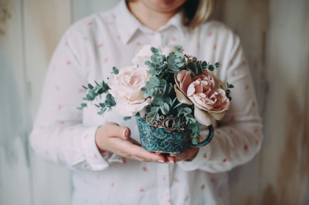 Flower arrangement in the hands of a florist woman in a decor studio. Close-upの写真素材