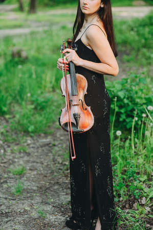 Beautiful girl holding a vintage violin in her hands. close-upの写真素材