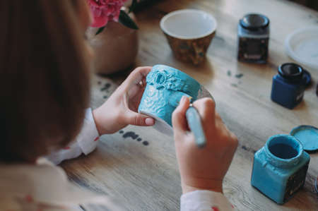 Woman working In her pottery studio. Ceramic workshop. Paint on clay mug in the pottery.の写真素材