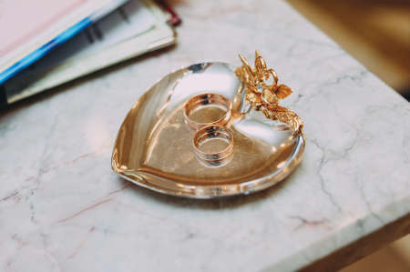 nice golden wedding rings lying on gilded round saucerの写真素材