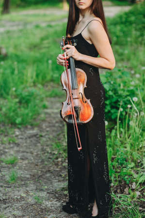 A young woman playing the violin in a magical forestの写真素材