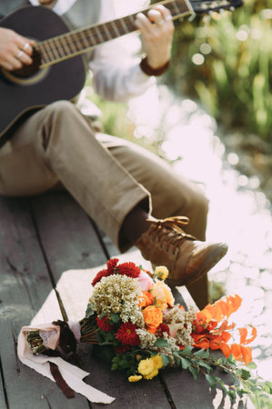 Handsome hippie style guitarist engrossed on music outdoors. Concept of freedom relaxation. close-up...