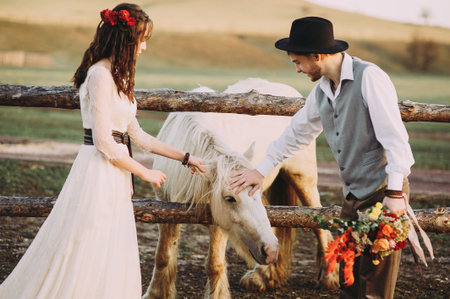 Stylish bride and groom are watching a horse. loft, rustic wedding walk