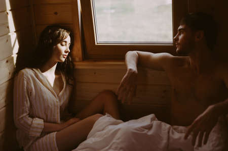 Unhappy couple sitting in bed away from each other. Woman in foreground.の写真素材