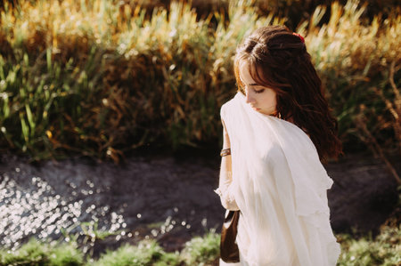 beautiful bride in a stylish light dress posing on the background of the river
