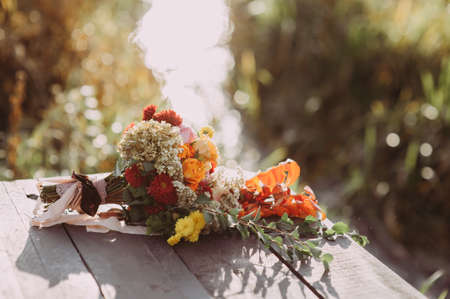 beautiful wedding bouquet of different flowers lies on a wooden bridgeの写真素材