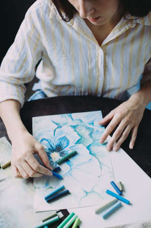 beautiful girl draws with pastel crayons on a window backgroundの写真素材