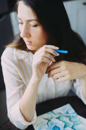 beautiful girl draws with pastel crayons on a window backgroundの写真素材