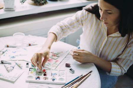 Beautiful girl artist paints with watercolors in a bright studio. Art. Drawing
