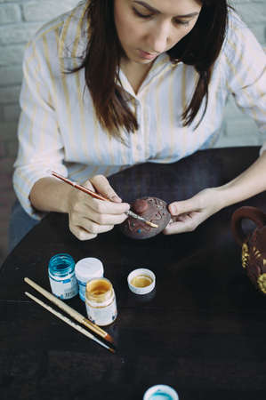 woman master paints the dishes at the workshop. clay teapot. handwork. Studio. designの写真素材