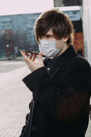 A guy in a protective medical mask calls on his cell phone. Virus protection. Coronavirusの写真素材