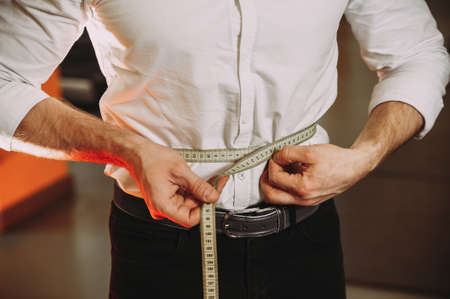 A man in a shirt holds a measuring tape. losing weightの写真素材