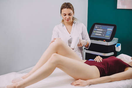 Beautician Giving Epilation Laser Treatment To Woman On Thighの写真素材