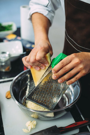 Chef grating cheese, chef hand grating parmesan cheese with grater, Chef rubbing cheese on a grater,...