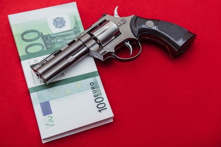 Gun and money on red velvet backgroundの写真素材