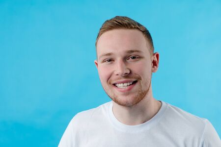 Young, red, handsome, guy smiles at the camera. The guy shows straight white teeth. He has a dazzling smileの写真素材