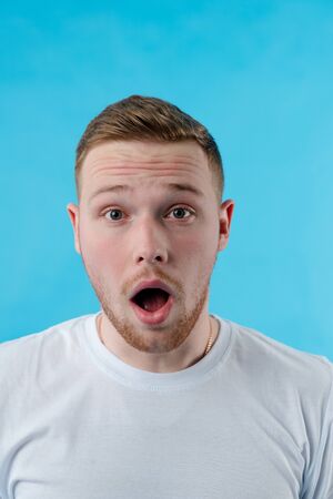 The red-haired guy in the white T-shirt is surprised to have his mouth open and his eyes wide.の写真素材