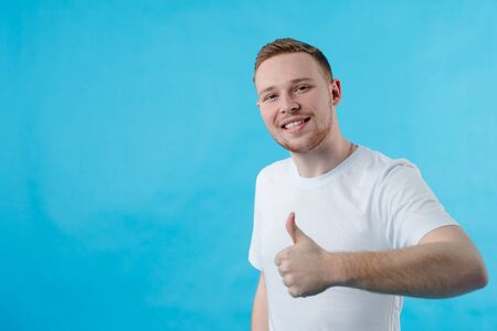 A red-haired guy of European appearance shows that everything is cool and super. Guy shows like and handの写真素材