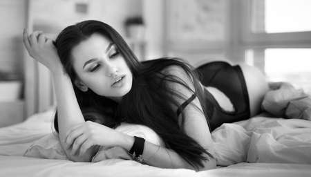 Beautiful young woman in white bathrobe in bedroom at home.の写真素材