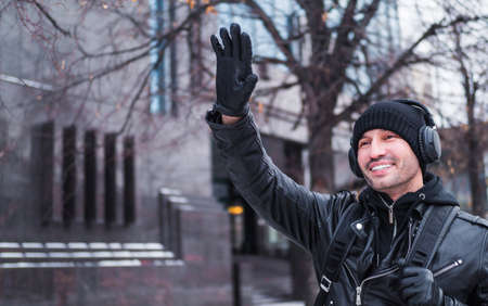 The man met a friend in the street in winter and waved to him. He listens to music through...